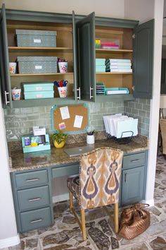 a kitchen with gray cabinets and marble counter tops, along with a chair in the middle