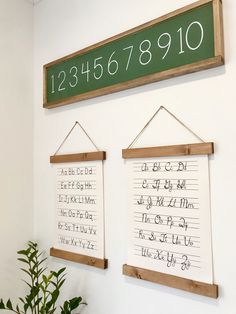 two wooden signs hanging on the wall above a potted plant