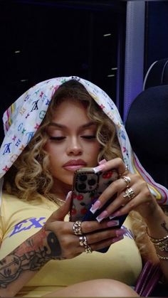 a woman with tattoos on her head looking at her cell phone while sitting in a car