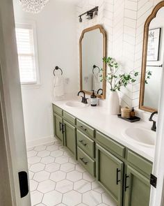 a bathroom with two sinks and mirrors on the wall, along with green cabinetry