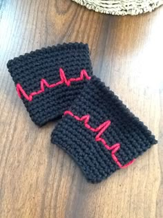 two knitted wrist warmers sitting on top of a wooden table