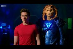 a man standing next to a statue of a lion in front of a blue background