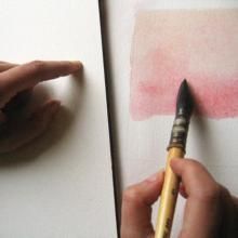 a person holding a brush and drawing on paper