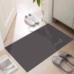 a pair of white shoes sitting on top of a floor next to a black mat