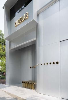 an entrance to a building with gold letters on the front and side walls that read choclab