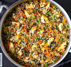 a pan filled with rice and vegetables on top of a wooden table