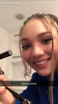 a woman is smiling while holding a hair dryer