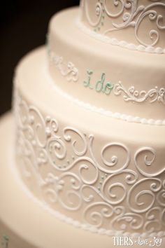 three tiered wedding cake with white frosting and green lettering on the top layer