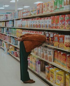 a woman standing in front of a grocery store filled with lots of cereal and milk