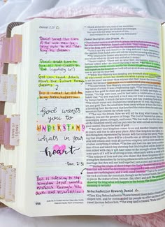 an open bible with colorful writing on the pages and pink furnishing around it