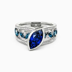 a ring with blue and white stones on it, set against a white background in the shape of a leaf