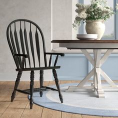 two chairs and a table in front of a window with white flowers on the table