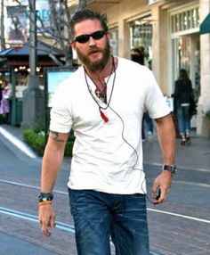 a man walking down the street with headphones in his ears and wearing sunglasses on