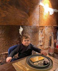 a little boy sitting at a table with food