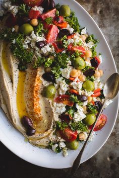 a white plate topped with lots of food and a fork on top of a table