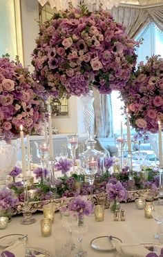 the table is set with purple flowers and candles