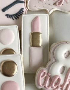 the cookies are decorated with pink icing and gold glitters, including lipstick, eyeshades, and eye shadow