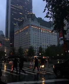 people crossing the street at night with umbrellas