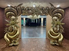 an entrance decorated with gold balloons and flowers in the middle of a hallway that leads to a hall