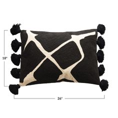 a black and white pillow with pom - poms on the bottom, measurements