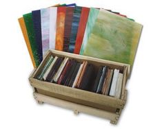 a wooden box filled with lots of different colored books on top of a white surface