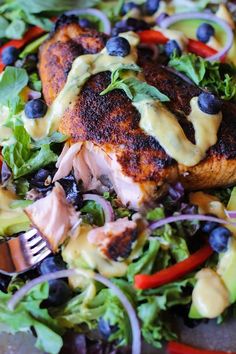 a salad with chicken, lettuce, blueberries and dressing on it is ready to be eaten