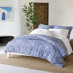 a bed with blue and white comforter in a bedroom next to a fireplace area