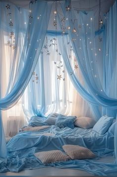 a bed covered in blue sheets and curtains with stars hanging from the ceiling above it