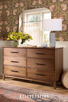 a dresser with flowers and a lamp on top