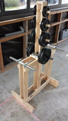 a wooden rack filled with black dumbbells on top of a floor next to a window