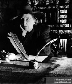 a woman sitting at a table with a feather quill and pen in her hand