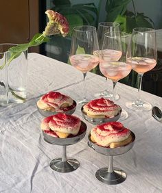 four desserts and three wine glasses on a table