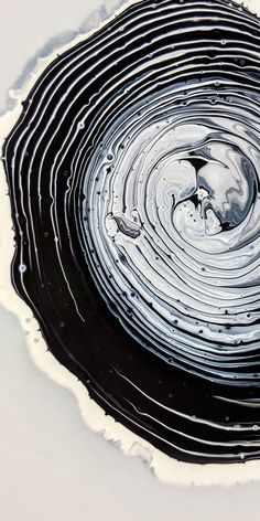 an abstract black and white painting with swirls in the center on a white surface