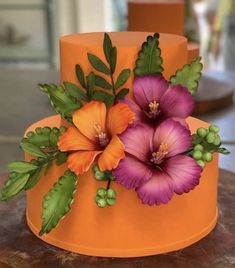 an orange cake decorated with flowers and greenery