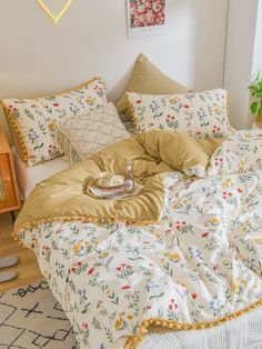 an unmade bed in a bedroom with flowers on the comforter and two pillows