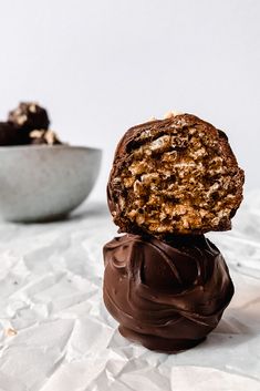 two pieces of chocolate and nuts on top of each other in front of a bowl