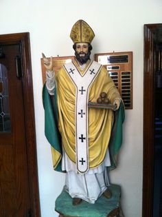 a statue of jesus holding a tray of food in front of a wall mounted plaque