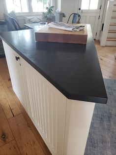 a black counter top in a kitchen next to a wooden floor