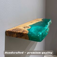 a wooden shelf with blue and green paint on it's edge in a bathroom