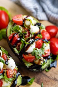 sliced avocado with tomatoes, mozzarella and other toppings on a cutting board