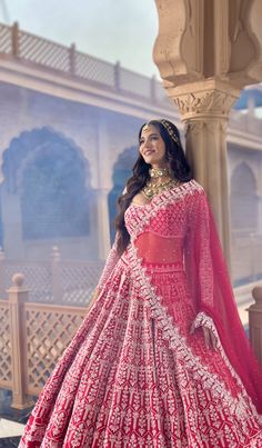 a woman in a red and white lehenga is posing for the camera with her hand on her hip