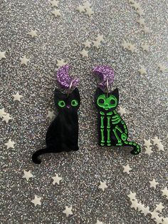 Black Cat Halloween Earrings Now with GLOW in the DARK options! your earrings will not glow in the dark unless you select the glow in the dark option These dangle earrings can be either cute or spooky, the choice is yours!  Choose from  a pair of cute kitties, pair of skeleton kitties, or even get a mismatched pair to have it both ways! The skeleton kitty is also offered in two colors.  The cats are made of black pearl acrylic, which has a subtle pearlescence to it. The cute kitties eyes and nose are engraved and hand painted in green and pink. The skeleton kitties are engraved as well and painted in either green or white. The green skeleton matches the cute kitty nicely, but I wanted to offer a traditional color as well.   The closures pictured are acrylic moon stainless steel studs. The Halloween Cat Ears Earrings, Halloween Cat Ears Earrings For Pierced Ears, Halloween Cat Design Earrings With Cat Ears, Skeleton Cat, Pastel Goth Outfits, Goth Tattoo, Black Cat Earrings, Earrings Kawaii, Cool Piercings