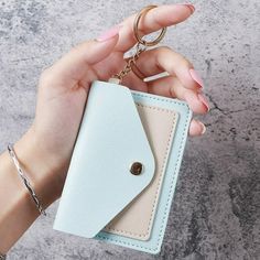 a person holding a small wallet with a keychain attached to the card holder