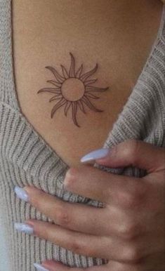 a woman's chest with a small sun tattoo on her left side ribcage