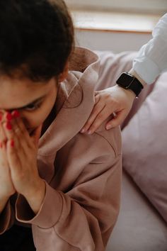 a woman covers her face while sitting on a couch