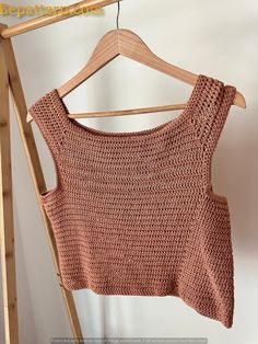 a knitted top hanging on a wooden hanger