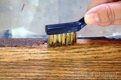 a hand holding a brush on top of a wooden table