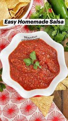 a white bowl filled with salsa surrounded by tortilla chips and cilantro