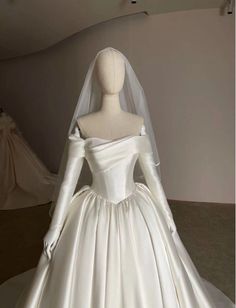 a white wedding dress on display in a room with mannequins behind it