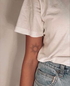 a woman's arm with a small sun tattoo on the left side of her right arm